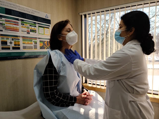 Doctor examining patients thyroid gland